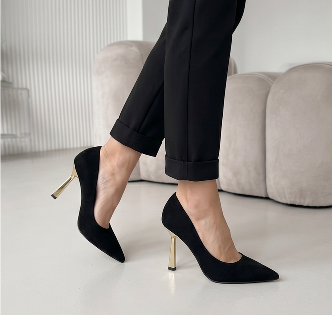 Black suede pointed pumps with a gold flared heel worn with black trousers